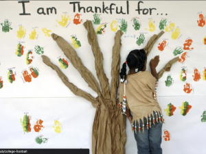 child putting handprint painting on wall to form a tree